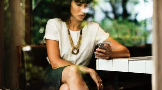 A woman looks at her phone in preparation for GDPR's affect on programmatic advertising.